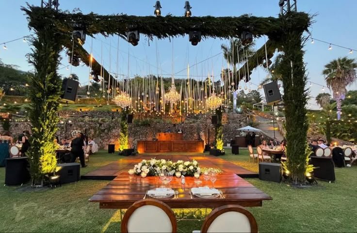 Evento al aire libre con arañas de luces, escenario y mesas